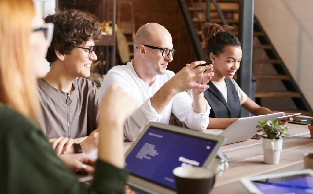A diverse group of individuals collaborating at a table, each using their laptops for a productive meeting.